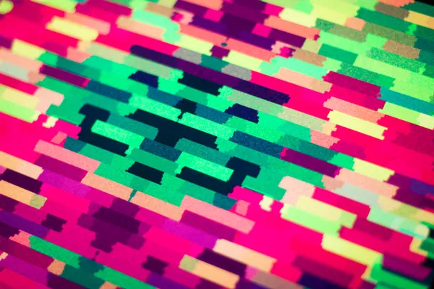 Angled close-up of a print's magenta, pink, and green horizontal bars, with shallow focus.