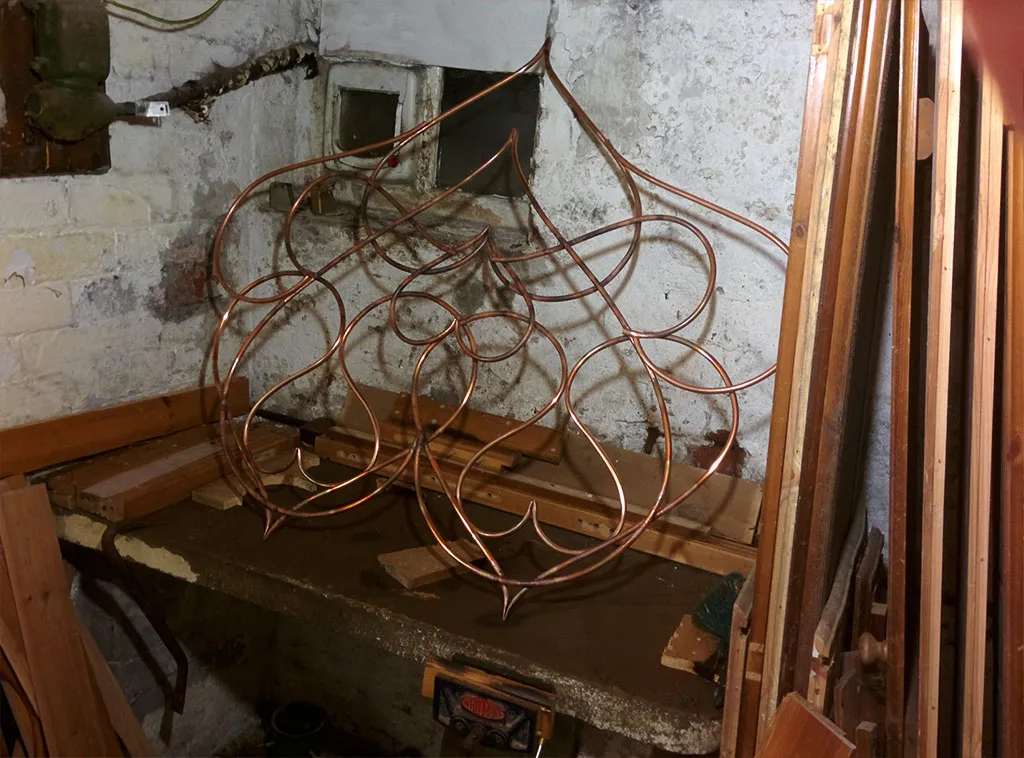 The near-complete copper structure propped up on a workbench in a brick cellar.