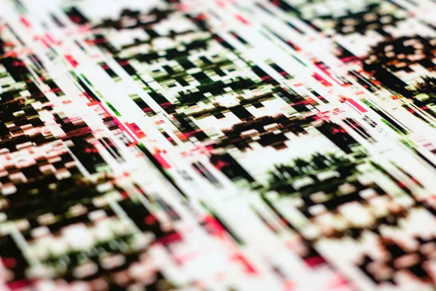 Angled close-up of a print's dense black, cream, and red pixel pattern.