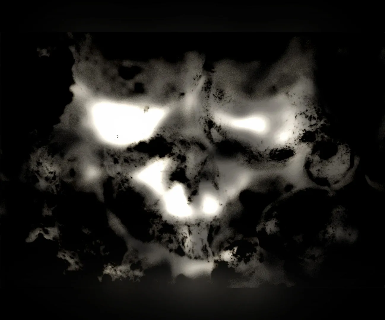 Grainy white patches on black that look like a grimacing face with two eyes and an open mouth.