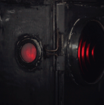 Animation of the lamp's small side window glowing red in the dark, next to the edge of the main lens.